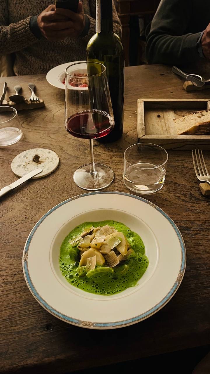 Un piatto della cucina locale e un calice di vino rosso su un tavolo di legno
