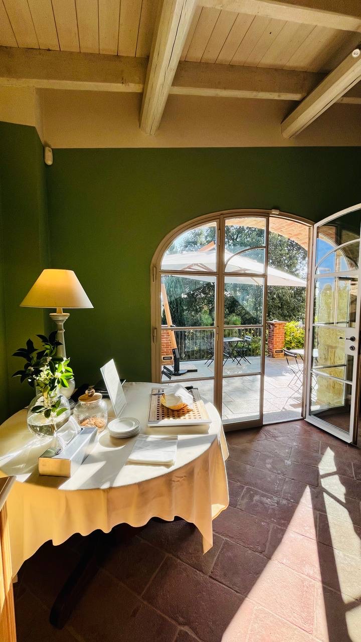 Sala con pareti verdi e porta ad arco aperta su una terrazza soleggiata